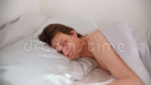 男人一个人睡在毯子下面的床上侧视视频的预览图