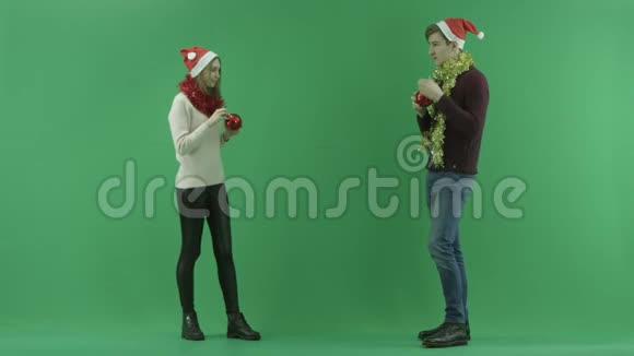 年轻夫妇在背景上用彩色钥匙装饰隐形圣诞树视频的预览图