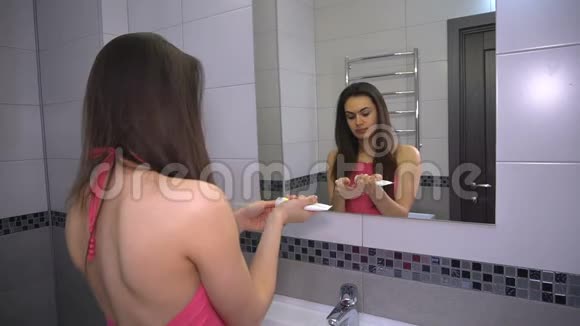 女孩把奶油涂在脸上准备化妆站在浴室里视频的预览图