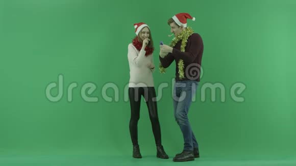 年轻的幸福夫妇庆祝圣诞节并在背景上用彩色钥匙互相拥抱视频的预览图