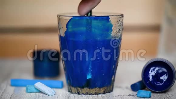 在透明的水玻璃中加入一滴蓝色油漆并搅拌水被污染了视频的预览图