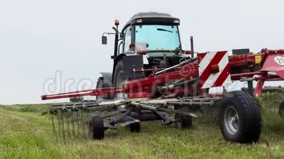拖拉机骑在农场边缘与联合马车收割草地视频的预览图