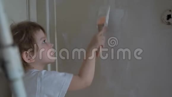 小可爱的女孩用油漆刷子和微笑粉刷墙壁视频的预览图