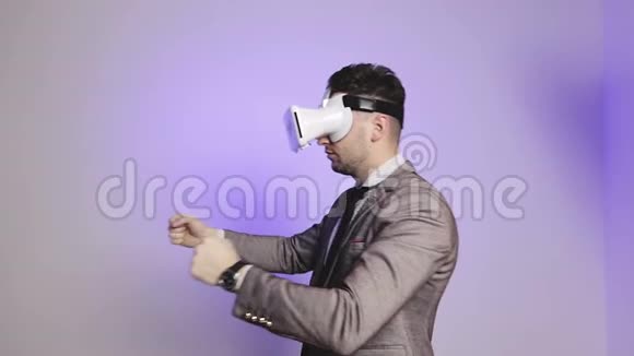 一个穿西装的优雅商人使用虚拟现实眼镜和舞蹈视频的预览图