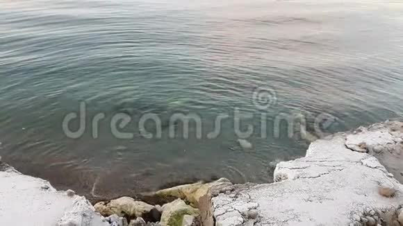挪威北部峡湾上的平静海浪冲击着积雪的海岸视频的预览图