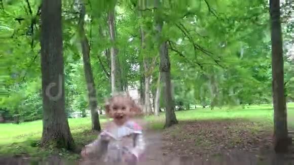 淘气的小女孩在镜头前穿过公园树小巷视频的预览图