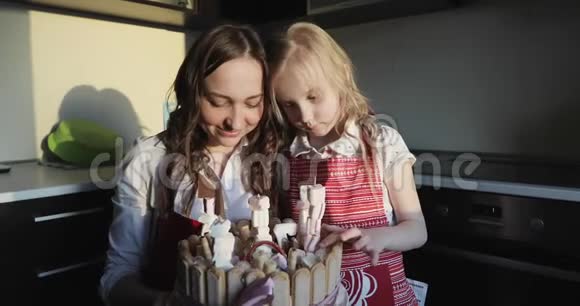 一位迷人的年轻母亲带着一个小女儿手里拿着一个漂亮的生日蛋糕视频的预览图