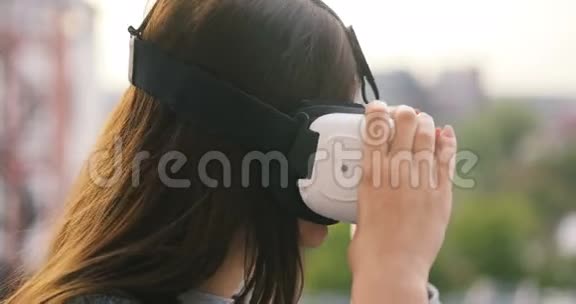 女用虚拟现实眼镜在屋顶建筑科技城市未来主义冒险女孩现代装置日落视频的预览图