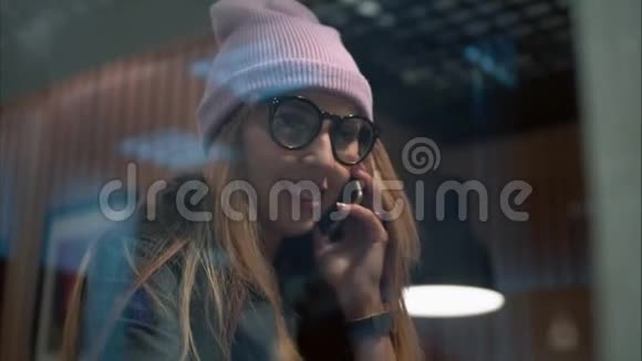 一位戴眼镜的时髦女郎在咖啡馆里打电话喝咖啡视频的预览图