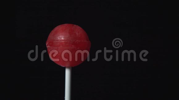 塑料棒上的糖果旋转作为黑色背景上的球的形式视频的预览图