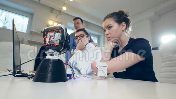 手被截肢的女孩正在观察科学家如何检查机器人手移动的连接视频的预览图