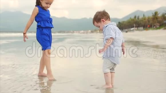 年轻的家庭孩子兄弟姐妹在海洋海岸附近玩耍幸福的家庭沿着海岸散步视频的预览图