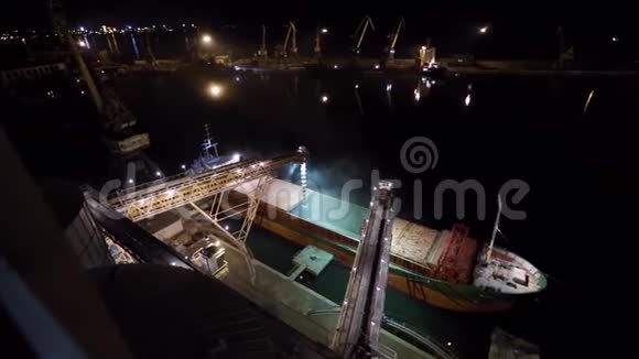 在海港的筒仓码头在散装货船上通过干线装载谷物作物到打开货舱的夜间全景图视频的预览图