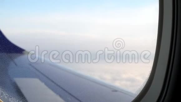 从飞机窗口的模糊视野机翼和多云的天空后面视频的预览图