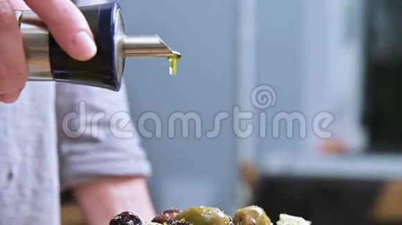 特写一只雌性手浇灌鲜纯素希腊色拉橄榄油天然食物健康生活方式视频的预览图