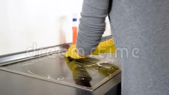 家庭主妇用黄色橡胶手套在厨房摩擦和清洁染色电炉的4k视频视频的预览图