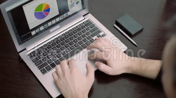 在办公室里用现代笔记本电脑打字的人那个人正在看手提电脑上的图表视频的预览图