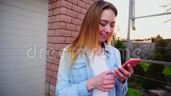 站在车库附近的年轻女孩她用智能手机近距离打字视频的预览图
