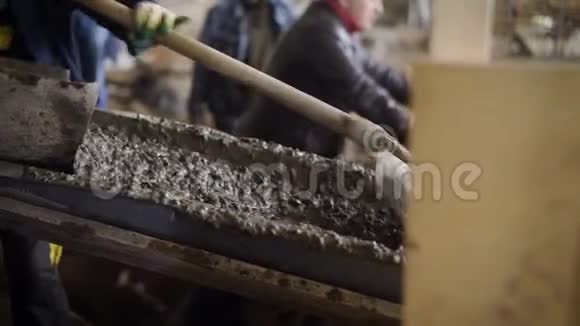 建筑工人用铁锹在施工区域的施工设备中移动水泥砂浆视频的预览图