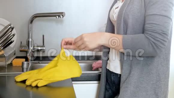 4k小家庭主妇站在厨房戴上黄色橡胶手套的特写镜头视频的预览图