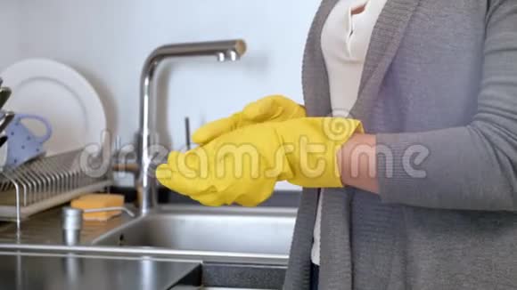 在厨房做家务后年轻家庭主妇脱下黄色乳胶手套的特写镜头视频的预览图