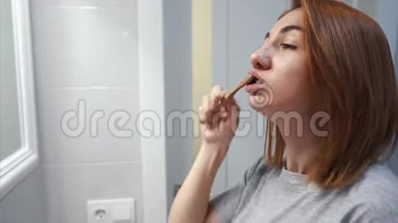 在浴室里刷牙的漂亮年轻女人视频的预览图
