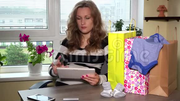 孕妇在木桌和许多购物袋上网上购物网站视频的预览图