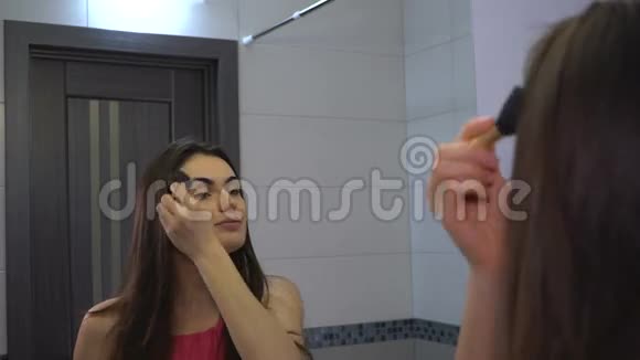 布鲁内特女孩用刷子在脸上涂上粉末早上化妆和护肤视频的预览图