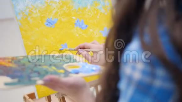 女人在黄色的背景上画蓝色的花视频的预览图