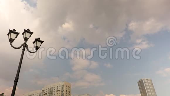 灯杆和城市建筑俄罗斯萨拉托夫云彩穿过蓝天延时录音4K录像UHD视频的预览图