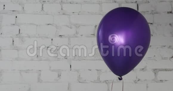 一个紫色气球放在白色砖墙背景上视频的预览图