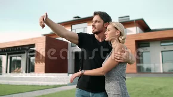 在豪华住宅附近的手机上拍照的快乐夫妇视频的预览图