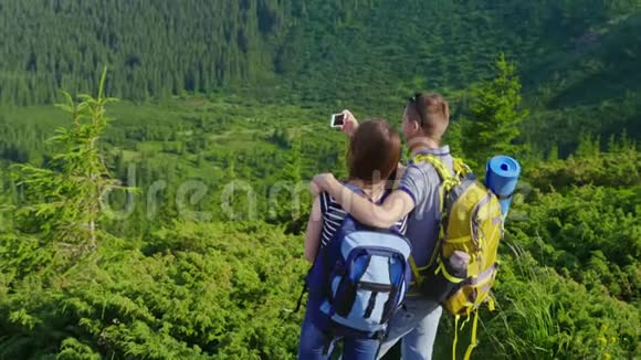 一对年轻夫妇被拍摄在一个风景如画的背景山上森林覆盖视频的预览图