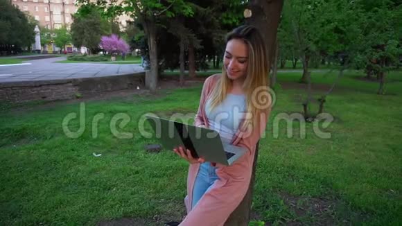 女孩在公园里用笔记本电脑聊天视频的预览图