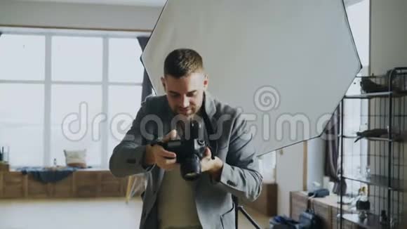年轻的摄影师在照相馆工作在数码相机上拍摄模特照片视频的预览图