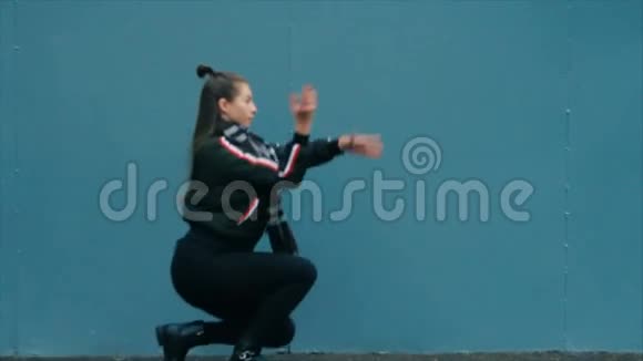 穿着黑色衣服的女人化妆在蓝漆砖墙上跳舞视频的预览图