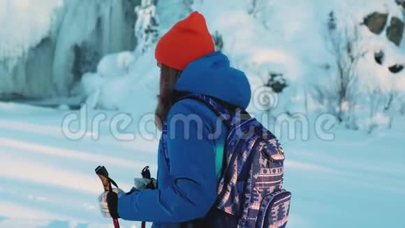 一个年轻的女孩登山者和一个徒步旅行者它正拿着拐杖在雪地里行走在这种背景下一场冰冻视频的预览图