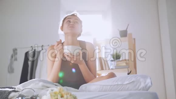 快乐的白种人女孩在床上慢慢地吃早餐有太阳耀斑的照片视频的预览图
