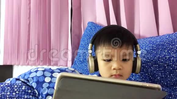 小孩戴着耳机在桌上看卡通视频的预览图