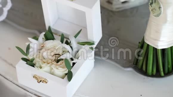 两个金色结婚戒指放在一个白色的木箱里里面放着玫瑰花视频的预览图