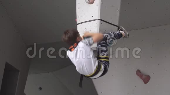 攀爬墙上的孩子一个小男孩在登山训练中爬上一块巨石孩子从事的是视频的预览图