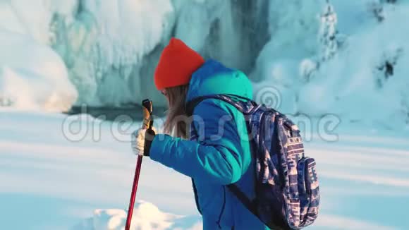 一个年轻的女孩登山者和一个徒步旅行者它正拿着拐杖在雪地里行走在这种背景下一场冰冻视频的预览图