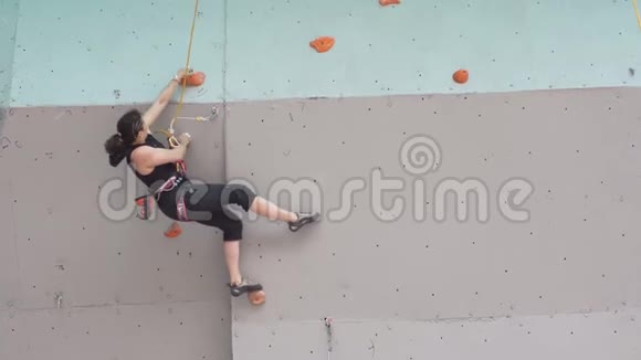 有登山设备的女登山运动员年轻的运动女孩爬上攀岩墙上的岩石视频的预览图