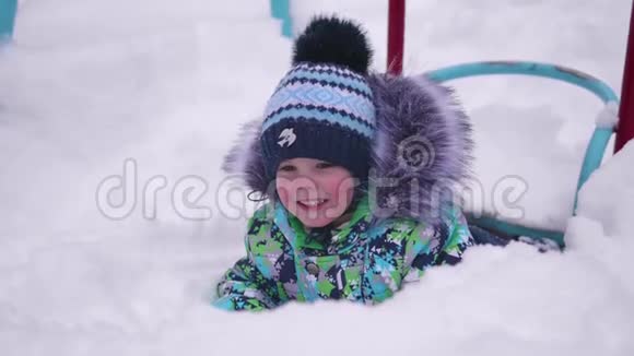 一个小孩在冬天的公园里玩雪躺在白色蓬松的雪上微笑的婴儿新鲜的乐趣和游戏视频的预览图