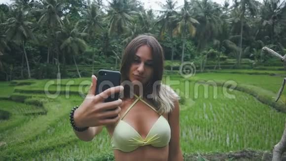 年轻女性在绿色热带森林享受大自然用智能手机自拍视频的预览图
