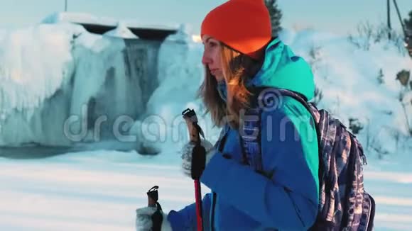 一个年轻的女孩登山者和一个徒步旅行者它正拿着拐杖在雪地里行走在这种背景下一场冰冻视频的预览图