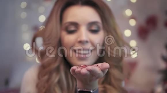 圣诞灯年轻迷人的女人吹纸屑慢节奏视频的预览图