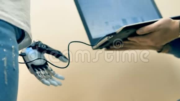 电子工程师使用笔记本电脑定制人手上的机器人手臂视频的预览图