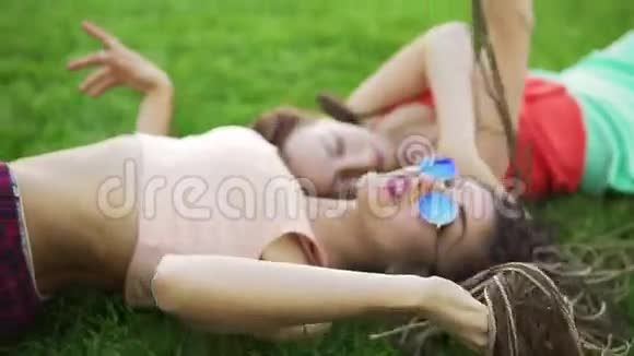 夏天的生活方式肖像两个时髦的女人躺在草地上享受美好的一天戴着明亮的太阳镜最好的视频的预览图