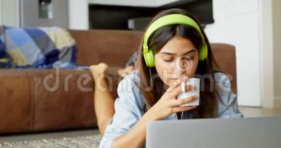 妇女在喝茶时使用笔记本电脑视频的预览图